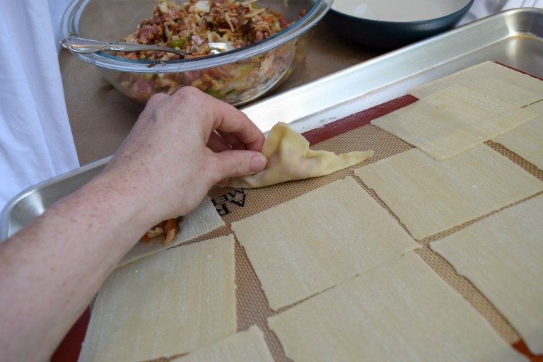 Pinching the potsticker shut.